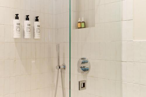 a bathroom with a shower with bottles on the wall at Att I Kvadraturen in Oslo