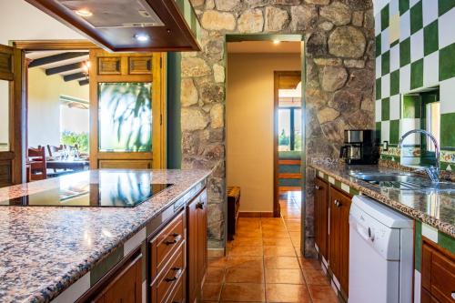 a kitchen with granite counter tops and a stone wall at Amaltea in Candeleda