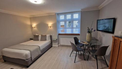 a bedroom with a bed and a table and a television at Aspen Hotel in London
