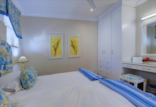 a white bedroom with a bed and a dresser at Makarios On Sea in Herolds Bay