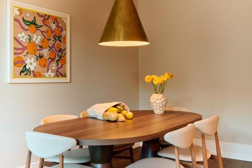 a dining room table with chairs and a vase of flowers at Att I Kvadraturen in Oslo