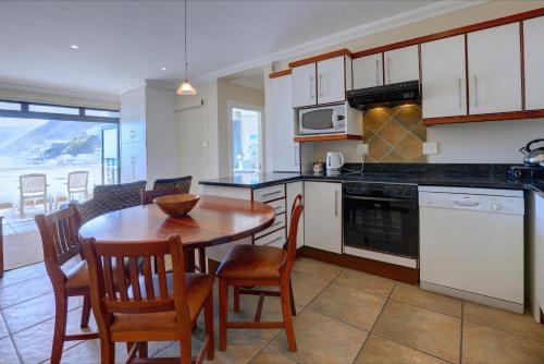 a kitchen with a table and chairs and a kitchen with a view at Makarios On Sea in Herolds Bay