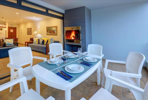 a dining room with a white table and chairs at Makarios On Sea in Herolds Bay