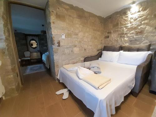 a bedroom with a white bed with a stone wall at Elen's Suites Pramanta in Pramanta