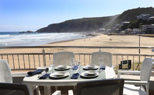 a table with plates and glasses on the beach at Makarios On Sea in Herolds Bay