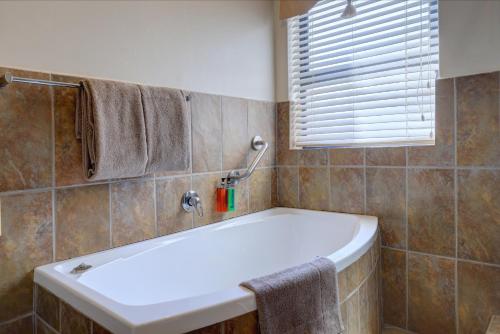 a bathroom with a bath tub and a window at Makarios On Sea in Herolds Bay
