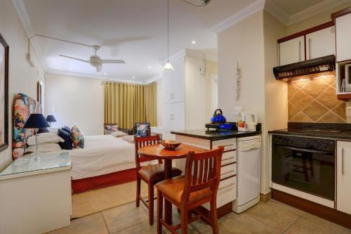 a kitchen and living room with a table and a bed at Makarios On Sea in Herolds Bay