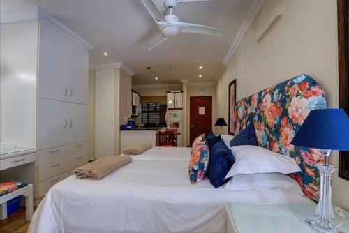 a bedroom with a large white bed with a blue lamp at Makarios On Sea in Herolds Bay