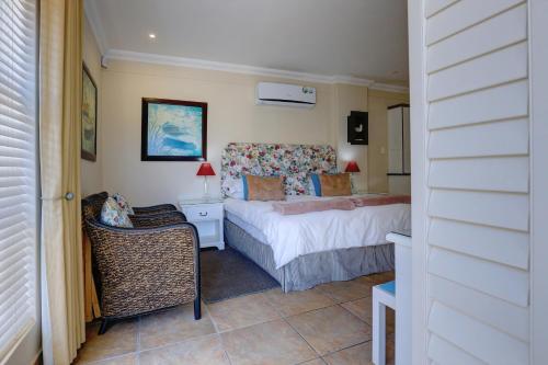 a bedroom with a bed and a chair in it at Makarios On Sea in Herolds Bay