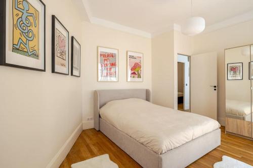 une chambre blanche avec un lit et quelques photos sur le mur dans l'établissement Exceptionnel près du Louvre & Opéra, à Paris