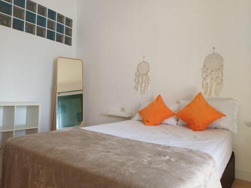 ein Schlafzimmer mit einem Bett mit orangefarbenen Kissen und einem Spiegel in der Unterkunft Casa Padrón! Paraíso junto al MAR in Puerto de Santiago