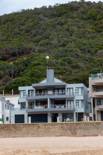 a building on the beach with a hill in the background at Makarios On Sea in Herolds Bay