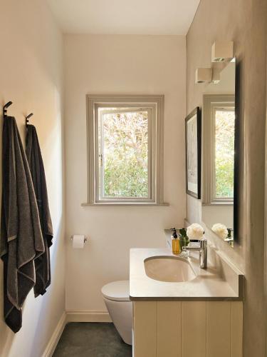 a bathroom with a sink and a toilet and a window at Kumbuk House in Franschhoek