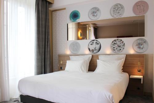a bedroom with a white bed with plates on the wall at Brit Hotel Limoges Centre Gare - Hôtel & Spa in Limoges