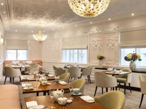 a restaurant with tables and chairs and a chandelier at St. Ermin's Hotel, Autograph Collection in London