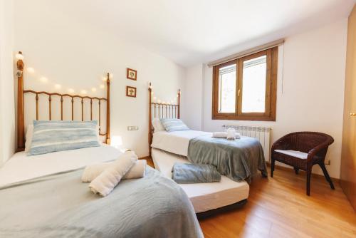 a bedroom with two beds and a chair at SantPauLux in Sant Pau de Seguries