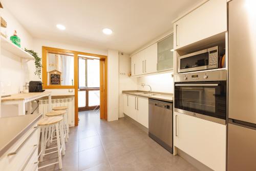 a kitchen with white cabinets and stainless steel appliances at SantPauLux in Sant Pau de Seguries