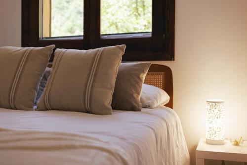 a bed with pillows in a bedroom with a window at SantPauLux in Sant Pau de Seguries
