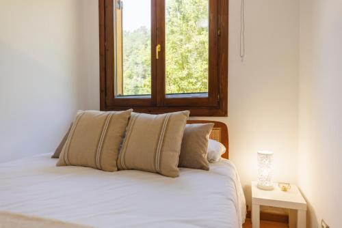 a bed with two pillows and a window in a room at SantPauLux in Sant Pau de Seguries