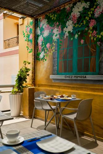 a table and chairs on a patio with flowers on the wall at Chez Mimosa Petite - Free Laundry in Ho Chi Minh City