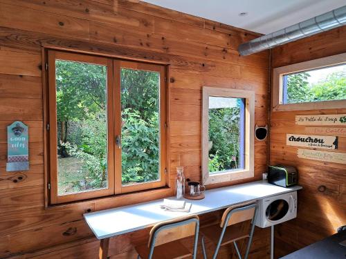 une chambre avec une table et deux fenêtres dans l'établissement La Cabane des Dunes, à Poitiers
