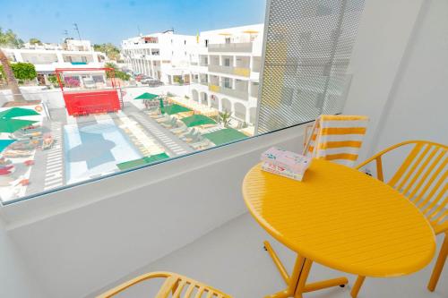 a yellow table and chairs on a balcony with a view of a pool at Ryans Lolas - Adults Only in San Antonio Bay