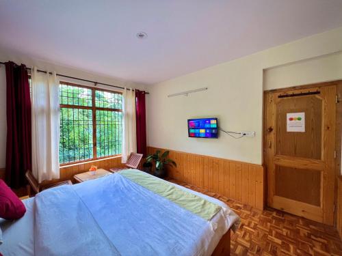 a bedroom with a large blue bed and a window at Urban Monk Stays and Cafe in Manāli