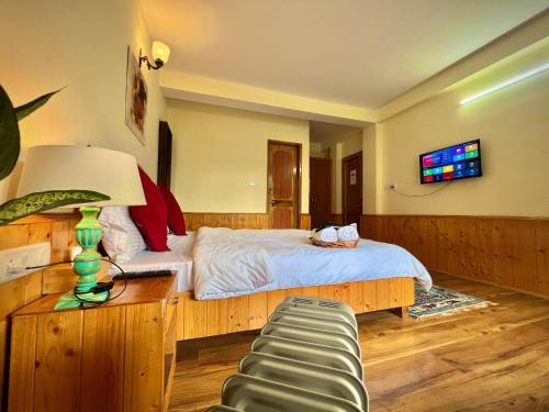 a bedroom with a bed and a table with a lamp at Urban Monk Stays and Cafe in Manāli