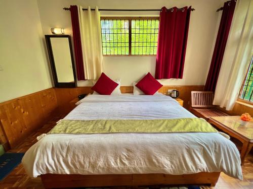 a bedroom with a large bed with red pillows at Urban Monk Stays and Cafe in Manāli