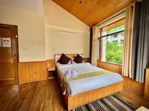 a bedroom with a large bed with a window at Urban Monk Stays and Cafe in Manāli