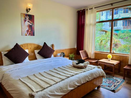 a bedroom with a large bed and a window at Urban Monk Stays and Cafe in Manāli