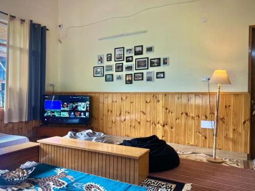 a living room with a bed and a tv at Urban Monk Stays and Cafe in Manāli
