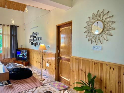 a living room with a large clock on the wall at Urban Monk Stays and Cafe in Manāli