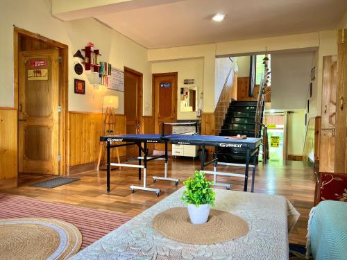 a living room with a ping pong table and stairs at Urban Monk Stays and Cafe in Manāli