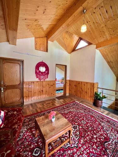 an open living room with wooden ceilings and a red rug at Urban Monk Stays and Cafe in Manāli