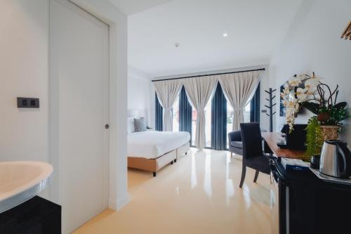 a white bedroom with a bed and a desk and a sink at Xinlor House - Phuket Old Town in Phuket Town