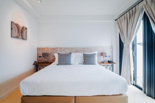a bedroom with a white bed and a large window at Xinlor House - Phuket Old Town in Phuket Town