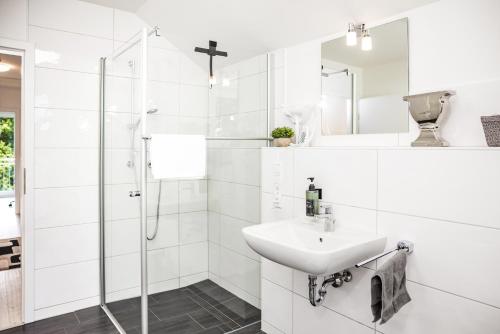 a white bathroom with a sink and a shower at FEEL - Comfort Haus Münsterblick - Nahe Münster in Senden