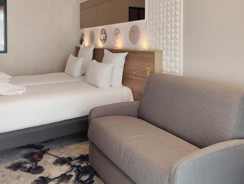a hotel room with a bed and a couch at Brit Hotel Limoges Centre Gare - Hôtel & Spa in Limoges
