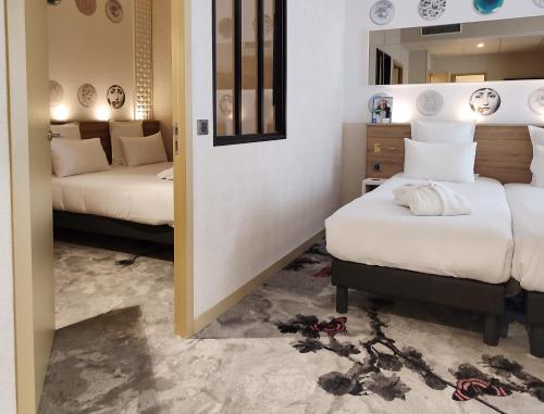 a hotel room with two beds and a mirror at Brit Hotel Limoges Centre Gare - Hôtel & Spa in Limoges