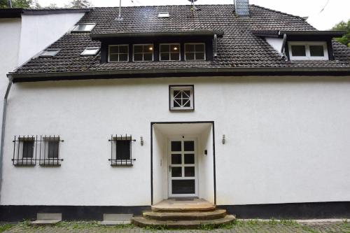 a white house with a black roof and a door at Bergmühle Simmertal in Simmertal