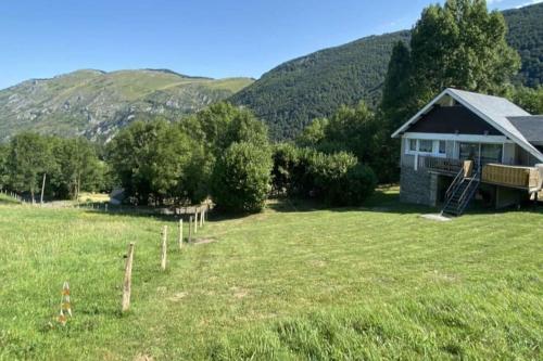 a house in a field with mountains in the background at Chalet au cœur de la montagne jacuzzi privé in Sainte-Marie-de-Campan