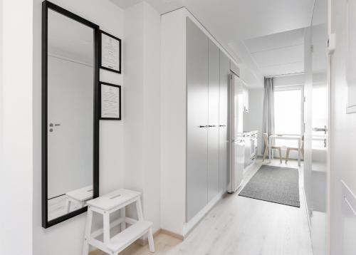 a white hallway with a mirror and a stool at Hiisi Homes Kangasala in Suorama