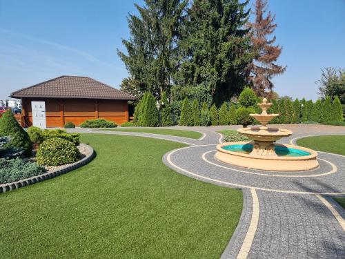 a fountain in the middle of a lawn with a house at Hotel Hesperus in Międzyrzec Podlaski