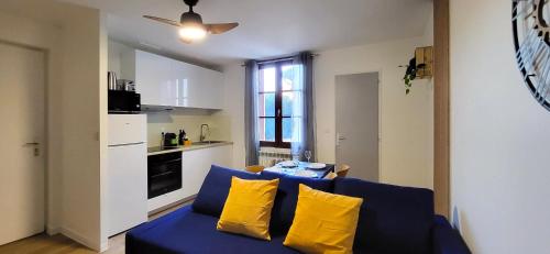 - un salon avec un canapé bleu et des oreillers jaunes dans l'établissement Colonial - Élégant deux-pièces à 20min de Rouen, à Caudebec-lès-Elbeuf