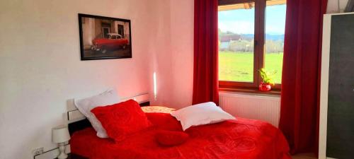 a red bed with red pillows in a bedroom with a window at Cazare Haiducita Bran in Zărneşti