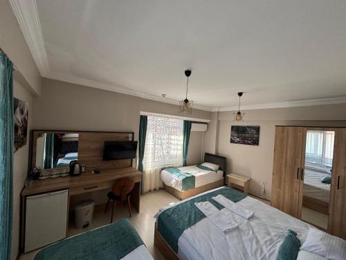 a bedroom with two beds and a desk and a television at Bolu Deluxe Otel in Bolu