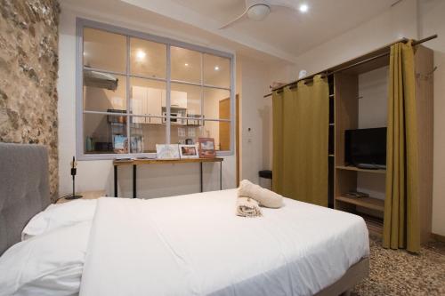une chambre avec un grand lit blanc et une télévision dans l'établissement Studio Roulet, ruelle au calme, à Arles