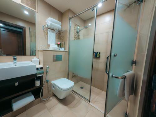 a bathroom with a shower and a toilet and a sink at Copthorne Downtown by Millennium in Abu Dhabi