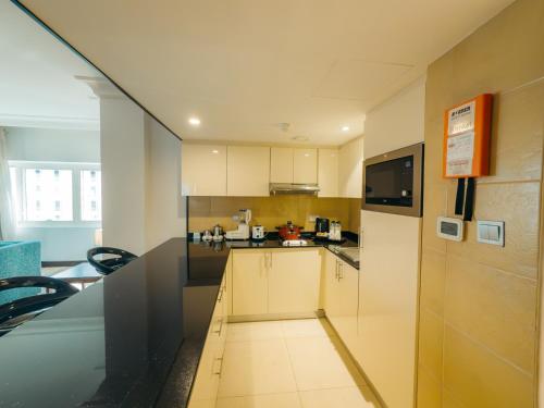 a kitchen with white cabinets and a black counter top at Copthorne Downtown by Millennium in Abu Dhabi